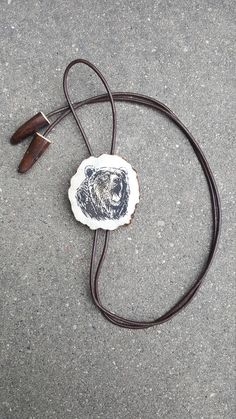 "Handmade bolo tie with engraved BEAR. Unique necklace with statement pendant from deer horn and long leather strip. Original gift for men. 100 % handmade. Great present for hunting, nature, wild animals, Western style lovers. ITEM DETAILS: * Horn thickness is ~ 1/4\" (6-7 mm), * Bolo tie diameter is ~ 2\" (5 cm). * Calibrated leather strap is 1/16\" (2 mm) thick, the ends are decorated with deer horn tips. Horn size, color and shape of this product can be different. ATTENTION FREE OPTIONS ----- Artisan Hand Tooled Jewelry, Western Lariat Jewelry As Gift, Western Style Lariat Jewelry As Gift, Western Style Lariat Jewelry For Gifts, Western Style Brown Jewelry With Adjustable Length, Brown Western Jewelry With Adjustable Cord, Brown Western Jewelry With Adjustable Length, Artisan Jewelry With Adjustable Length As Gift, Artisan Jewelry With Adjustable Length For Gift