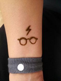 a wrist tattoo with glasses and a lightning bolt on it