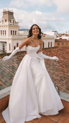 a woman standing on top of a roof wearing a white dress