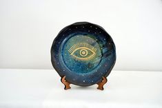 a decorative bowl with an eye painted on the front and bottom, sitting on a white surface