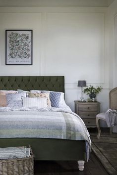 a bedroom with a bed, two chairs and a painting on the wall above it