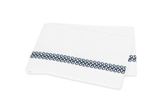 two white napkins with blue trim on top of each other, one folded and the other unwrapped