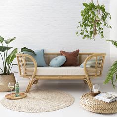 a living room with plants and wicker furniture on the floor next to a white brick wall