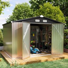 a small metal shed sitting on top of a wooden deck next to a lush green field