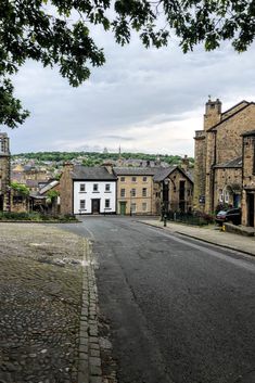 an empty street with buildings on both sides and trees in the middle of the road