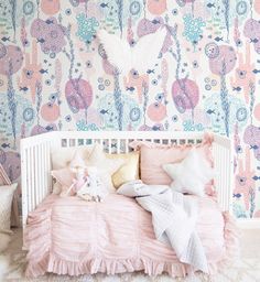 a white crib with pink and blue wallpaper in the background, along with two stuffed animals