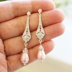 a pair of earrings with pearls and diamonds on the bottom of each earring is being held in someone's hand