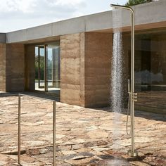 a water spouting from the side of a building in front of a glass door