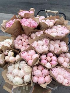 a pile of pink and white flowers sitting next to each other on top of brown paper bags