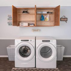 a washer and dryer in a laundry room with wooden cabinets above them,