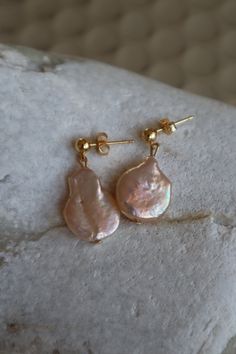 Dulcis - Sweet & Charming A peachy natural biwa pearl in a lovely drop shape hanging from a 24K gold plated round setting. The slightly asymmetrical pearls measures 1.5 x 2 cm and 1.3 x 1.7 cm and the total length of the earrings are 2.5 cm. Our jewelry comes in a stylish and safe packaging, ready to be gifted to a special person or to yourself. Handmade in Nitentia's studio in Stockholm, Sweden. We use all natural pearls and genuine gold plated settings. Please join Nitentia on Instagram for in High Luster Teardrop Pearl Earrings, High Luster Drop Pearl Earrings For Gift, Gold Briolette Pearl Earrings With High Luster, Pear-shaped High Luster Pearl Earrings, Pear-shaped High Luster Pearl Earrings Gift, Gold High Luster Dangle Pearl Earrings, High Luster Gold Dangle Pearl Earrings, High Luster Briolette Pearl Earrings As Gift, Gold Dangle Pearl Earrings With High Luster