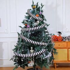 a decorated christmas tree with black and white striped ribbons on it's top, in a living room