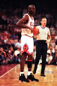 a man holding a basketball while standing on top of a court