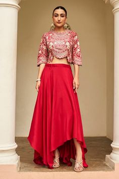 Carmine red top with all over floral embroidery using zardozi, aari work, french knots, and dori work. Paired with an asymmetric skirt. - Aza Fashions