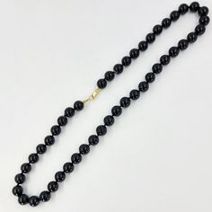 This onyx bead necklace features 8mm black onyx beads measuring 16 inches in length and with a 14 Karat yellow gold clasp.