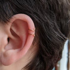 a close up of a person wearing a gold ear cuff