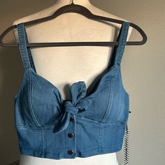 Trendy Denim Sleeveless Crop Top By Haute Monde Features A Built In Padded Chest And Thick Shoulder Straps. This Top Has Lots Of Stretch And There Is A Front Closure That Includes A Tie And 3 Snap Buttons. This Cute Crop Is Very Versatile! You Can Dress It Up Or Down, Layer It, And It Also Pairs Well With Other Denim * Please Note There Is A Flaw Shown In The Last Photo - The Back Piece Of The Middle Snap Button Is Missing. Super Easy Fix And The Button Replacement Can Be Found At Walmart For $1 Casual Medium Wash Denim Tank Top, Casual Blue Denim Vest For Summer, Denim Blue Cropped Tank Top For Spring, Dark Wash Sleeveless Casual Top, Casual Denim Blue Vest Top, Denim Blue Cropped Denim Tank Top, Denim Blue Cropped Tank Top, Cropped Denim Blue Tank Top, Dark Wash Denim Sleeveless Tank Top