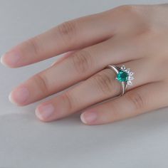 a woman's hand with a ring on it and a green stone in the middle