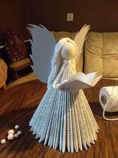 an angel made out of books sitting on top of a wooden table next to yarn