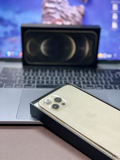 an open laptop computer sitting on top of a table next to a cell phone and speaker