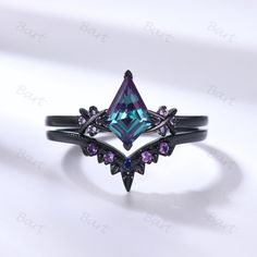 an unusual ring with blue and purple stones on it's sides, sitting on a white surface