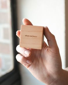 a person holding a small wooden block with the words always and forever on it