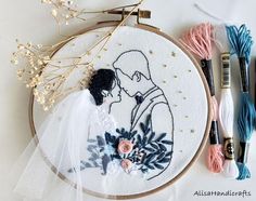 the embroidery is being worked on with scissors and thread to make it look like they are kissing