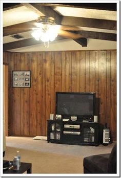 a living room with wood paneling and a television in the corner on an entertainment center