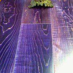 a vase with flowers sitting on top of a purple table cloth covered in wood planks