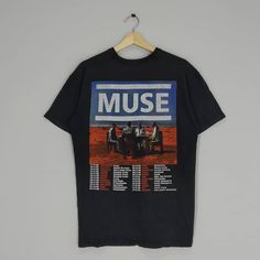 a black t - shirt with an image of three people in front of the words muse on it