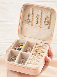 a person holding an open jewelry box with rings and bracelets in it on a table