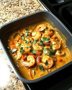 a pan filled with shrimp and vegetables on top of a stove