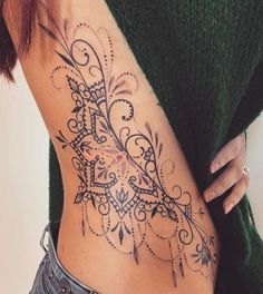 a woman's stomach with an intricate tattoo design on her lower back and side