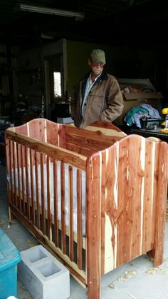 a man standing next to a wooden baby crib in a garage filled with tools