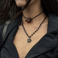 a close up of a woman wearing a black shirt and necklace with flowers on it