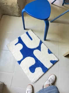 a blue and white rug on the floor next to a chair with someone's feet in it