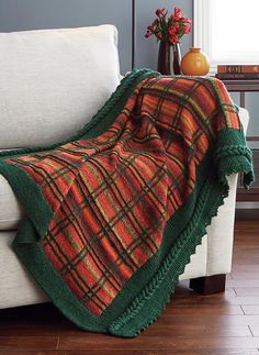 a couch with a blanket on top of it next to a vase filled with flowers