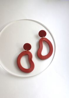 a pair of red earrings sitting on top of a white plate