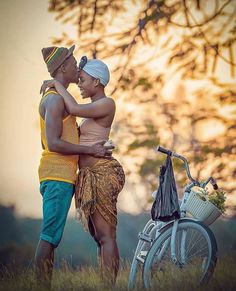 two people standing next to each other near a bike