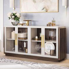 a white and brown cabinet with glass doors in a room next to a painting on the wall