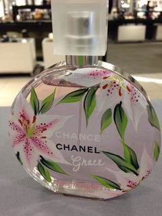 a bottle of chanel grace perfume sitting on a table in a room with tables and chairs