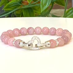 Embrace the soothing and loving energies of Rose Quartz with this exquisite bracelet. It features Grade AAA Madagascar Rose Quartz beads, renowned for their unconditional love and inner  properties. Available in 6mm or 8mm bead size.  For added elegance and charm, the bracelet is adorned with a silver-color heart-shaped Cubic Zirconia lock, signifying the love and compassion Rose Quartz represents. Rhinestone spacers enhance the bracelet's overall aesthetic. Crafted with high-quality pink stretc Spiritual Rose Gold Bracelets With 8mm Beads, Spiritual Rose Gold Bracelet With 8mm Beads, Healing Beaded Bracelets With Round Beads For Valentine's Day, Elegant Rose Quartz Stretch Bracelet With Round Beads, Elegant Heart Beads Stretch Bracelet Gift, Elegant Heart Beads Stretch Bracelet For Gift, Rose Gold Bracelets With 8mm Beads For Gift, Rose Gold 8mm Beads Bracelet For Gift, Rose Gold 8mm Beads Bracelet As Gift