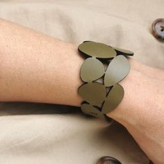 a woman's arm wearing a green bracelet with leaves on it