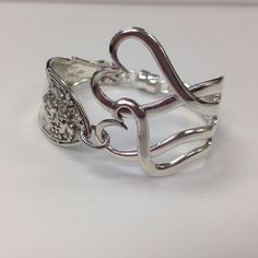 a silver ring with two intertwined hearts on it's sides, sitting on a white surface