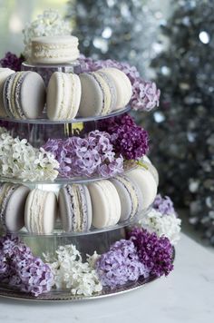 a three tiered cake with macaroons and flowers on it in front of a christmas tree