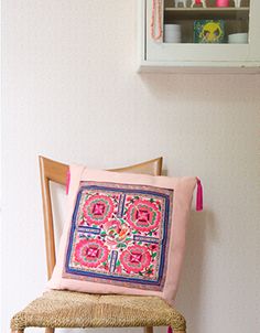 a pink pillow sitting on top of a wooden chair next to a wall mounted shelf