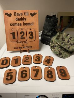 a table topped with lots of wooden tags next to a sign that says days till comes home