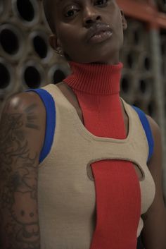 an image of a woman with tattoos on her arm and neck, looking at the camera