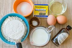 ingredients to make cake sitting on top of a wooden table next to eggs and flour