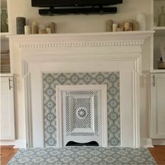 a fireplace with a tv above it in a room that has white cabinets and shelves